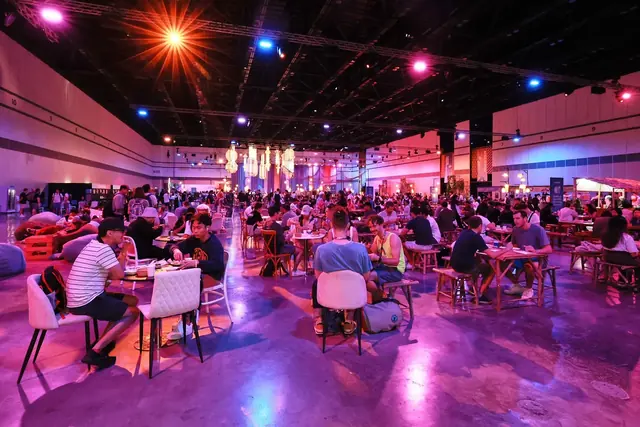 People gathering at tables beneath lanterns at Devcon SEA.