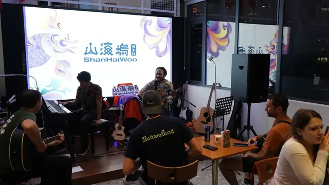 Adults playing guitars and keyboards together in the ShanHaiWoo room.