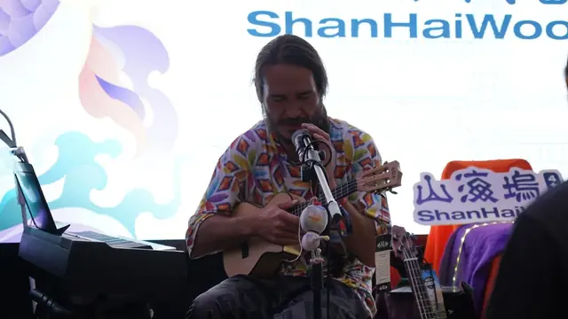 A musician singing and playing a small stringed instrument at ShanHaiWoo.